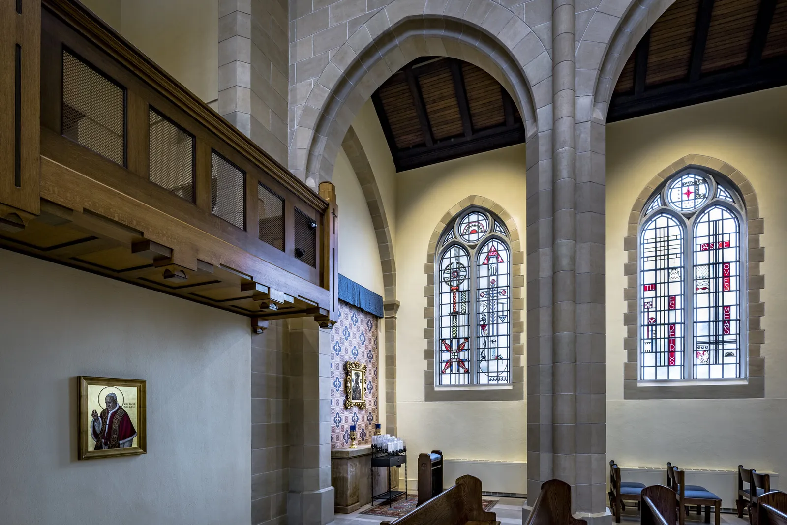 The side aisle: stone piers, arched windows and a framed icon beneath the timber gallery.